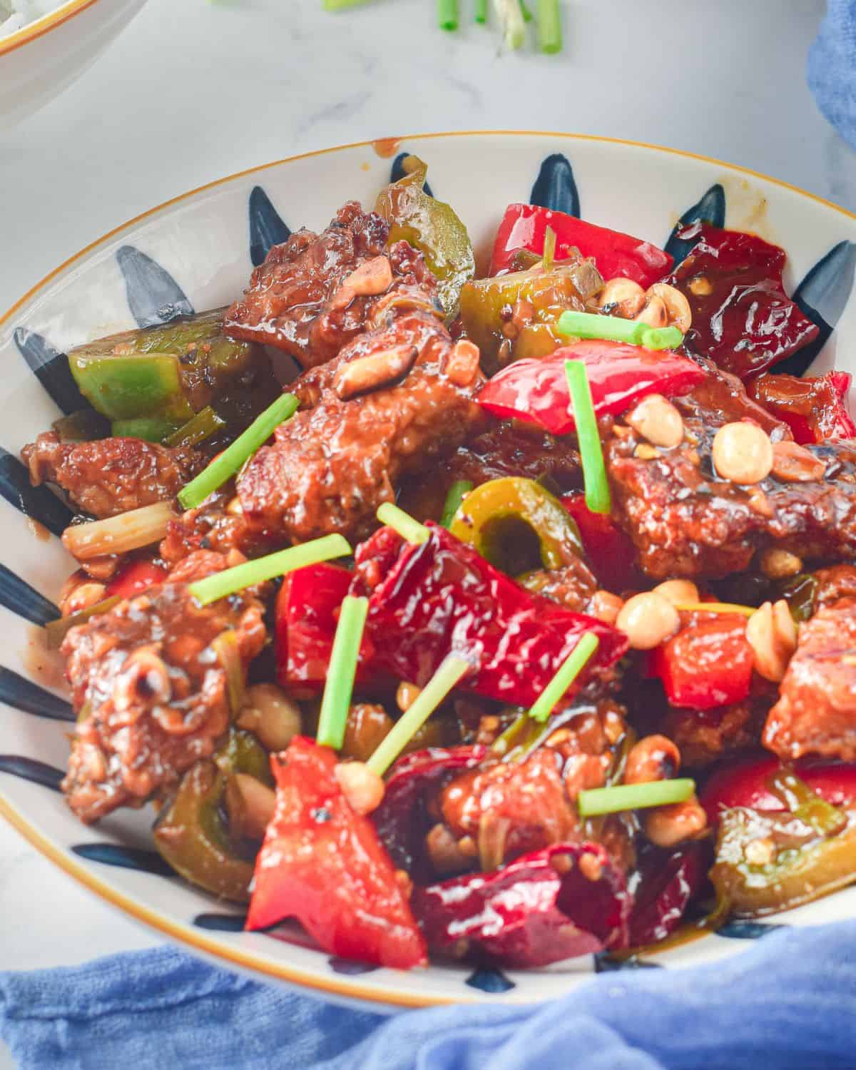 Air Fryer Kung Pao Chicken with red chillies, peppers in a bowl.