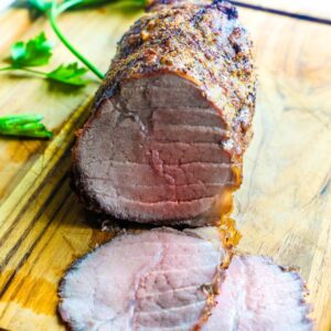 A roasted eye round roast on a cutting board sliced.