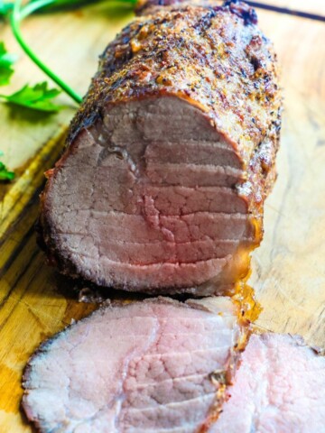 A roasted eye round roast on a cutting board sliced.