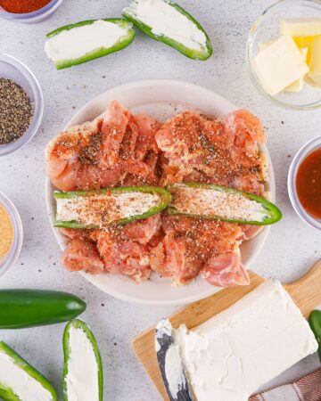 Seasoned chicken thighs cut open with jalapenos stuffed with cream cheese and topped with seasoning. 