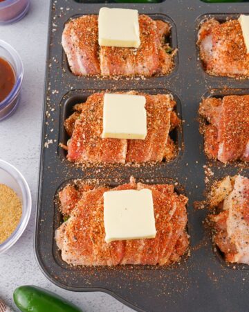Bacon wrapped boneless chicken thighs with jalapeno cream cheese popper filling in a loaf pan.
