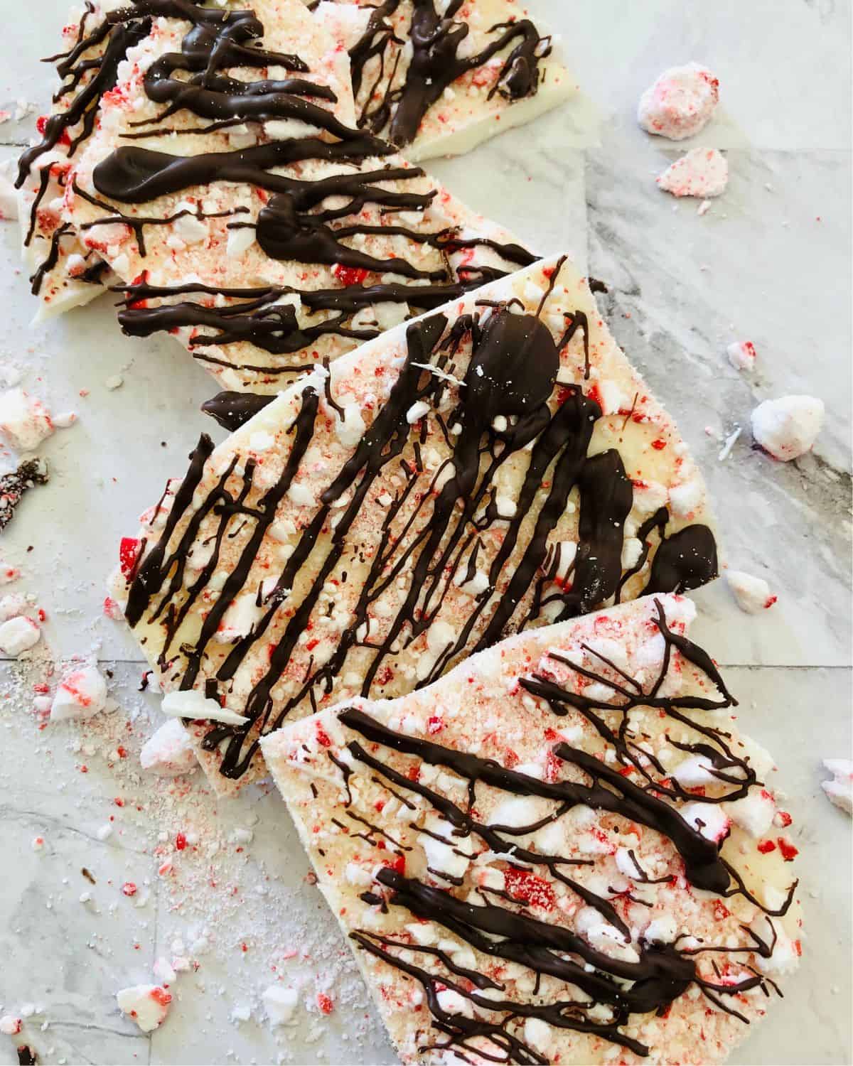 White chocolate peppermint bark pieces with crushed peppermint and drizzled chocolate.