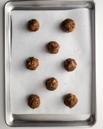 A baking sheet with uncooked cookie dough to make browned butter pecan chocolate chip cookies.