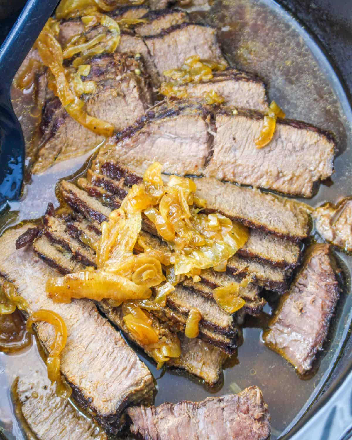 Slow Cooker Flank Steak with onions in a slow cooker vessel.