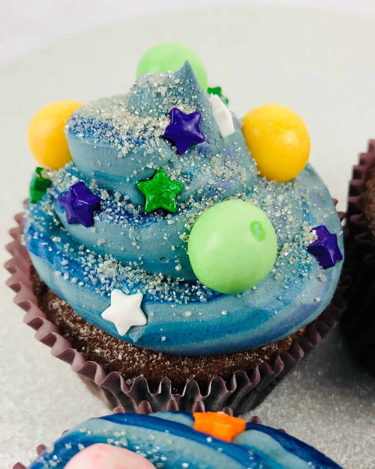 A blue galaxy themed cupcakes with jelly beans and star candy decorations. 