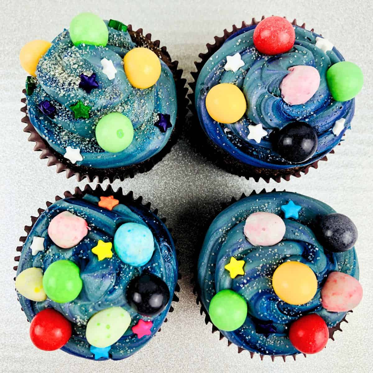 Chocolate cupcakes decorated with galaxy theme treats and a blue sky themed frosting.