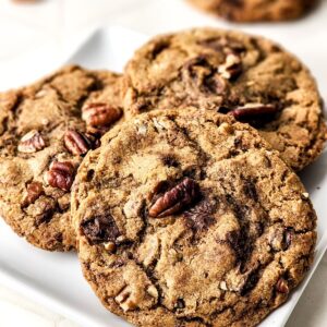 Chocolate chip brown butter cookies with pecans on a plate.