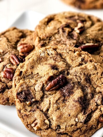 Chocolate chip brown butter cookies with pecans on a plate.