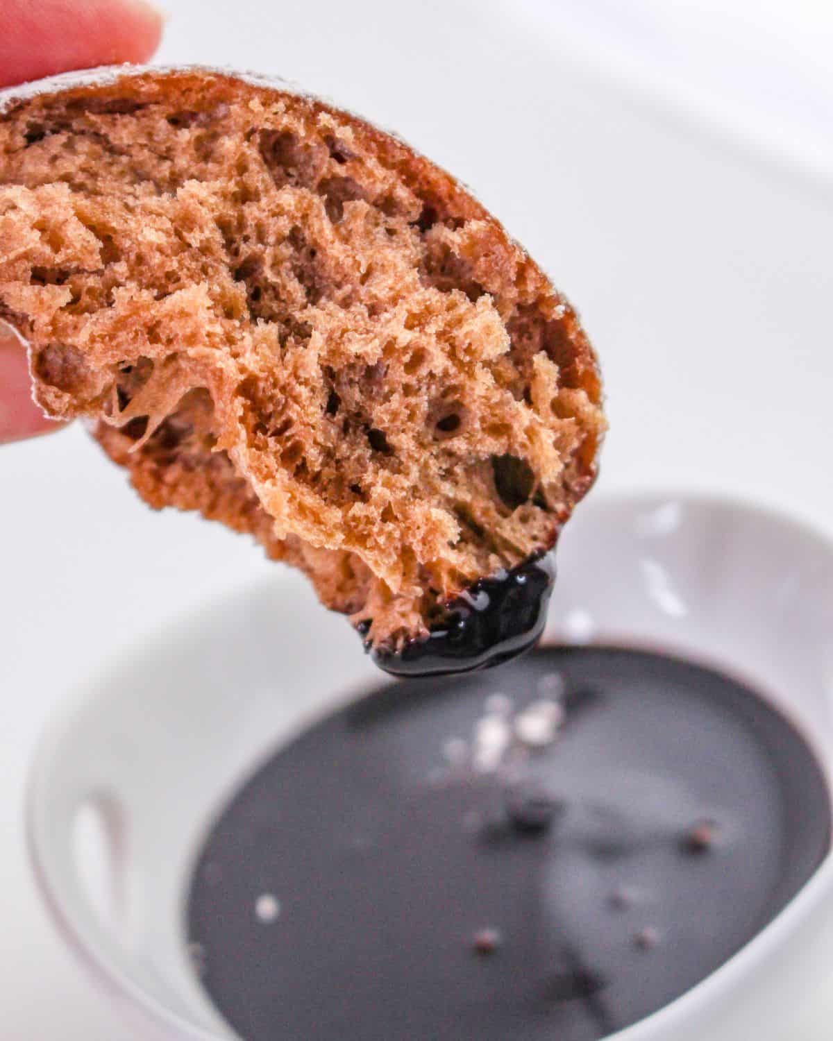 Chocolate flavored beignet dipped into a chocolate sauce.