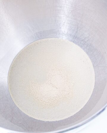A large mixing bowl with yeast and water blending to make beignets.