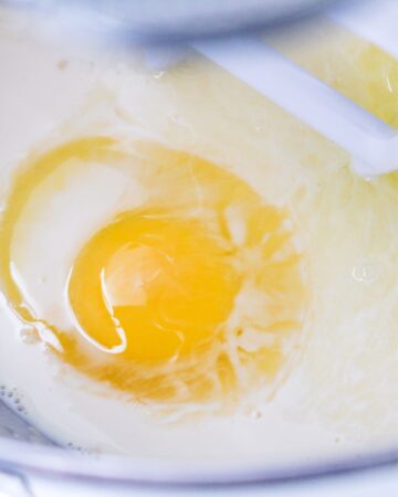 A mixing bowl with yeast and eggs to make chocolate beignets.
