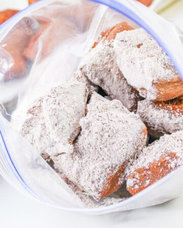 Chocolate beignets that have been fried and sprinkled with powder sugar. 