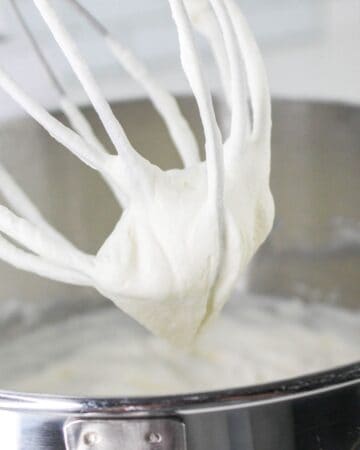 A large beater with cream on the whisk after being beaten for ice cream.