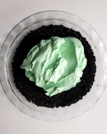 Glass pie plate with an oreo crumble crust and a green mint pie filling.