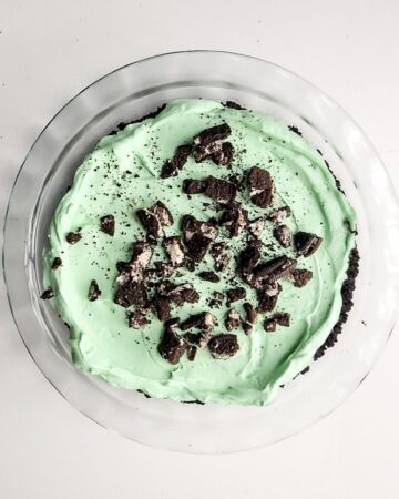 Grasshopper creamy pie topped with chocolate cookie cream crumbles in a glass pie plate.
