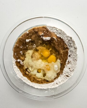 A mixing bowl with wet ingredients mixing into dry ingredients to make a carrot cake.