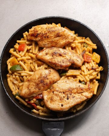 A saute pan with chicken in fajita seasoning amd pasta.