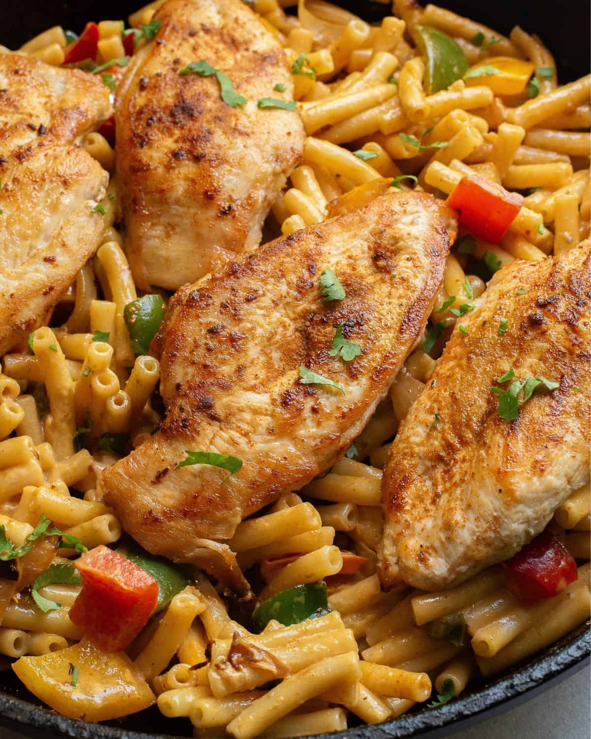 Chicken breasts and pasta with peppers in a large skillet to make fajita pasta.