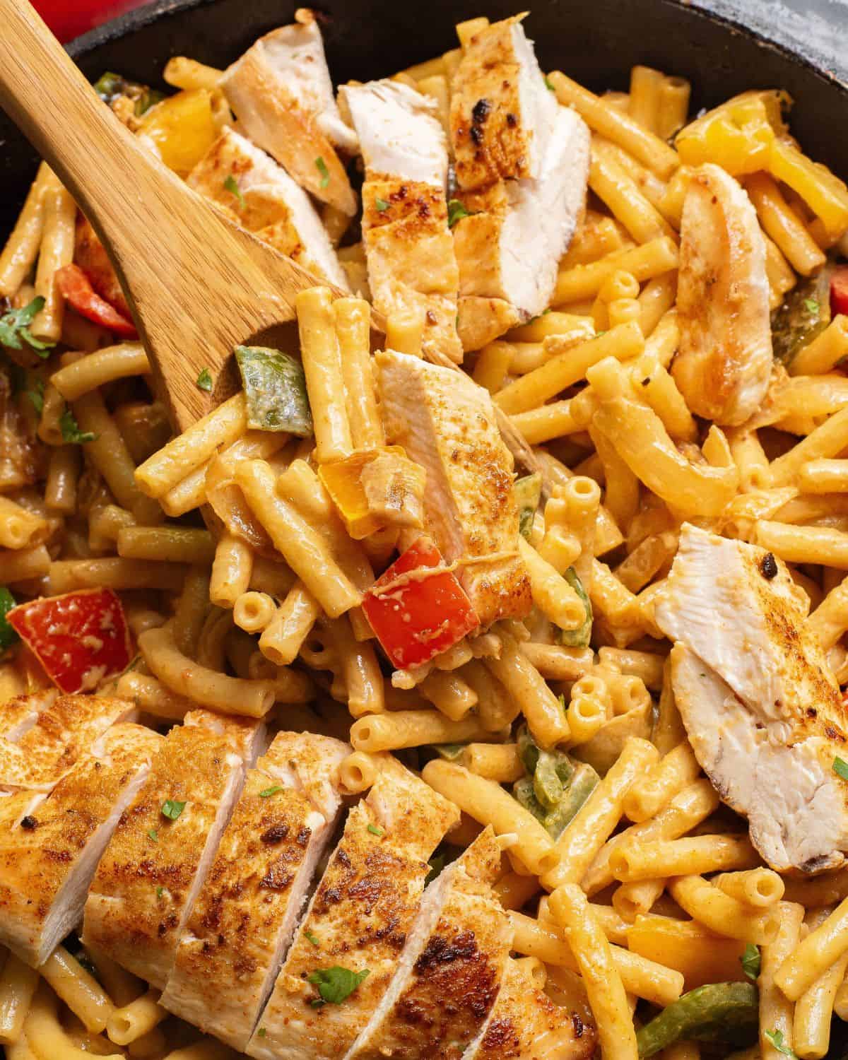 One pot chicken fajita pasta in a pan with sliced cooked chicken, peppers, and penne pasta.