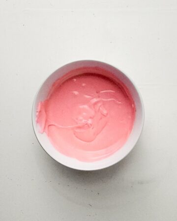 A bowl of cheesecake mixture with pink food coloring.