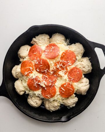 Pizza dough with a cheesy center dip for pizza dip in a cast iron skillet.