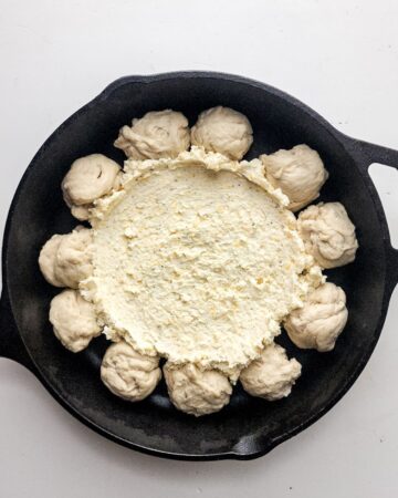 Pizza dough and cheese in a cast iron pan to make pizza dip.