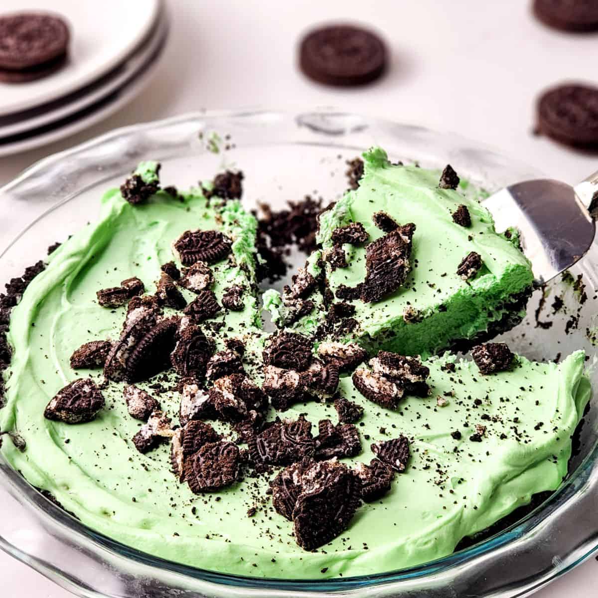 A grasshopper mint pie with oreo crumbles on top of the pie in a glass pie plate.