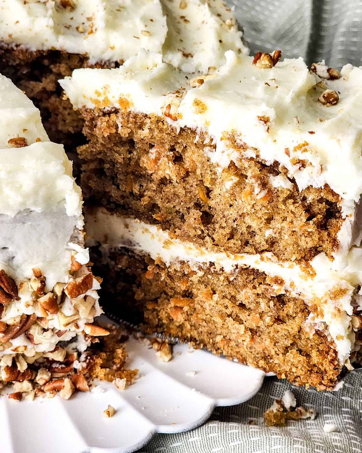 A slice of layered carrot cake being picked up out of the cake.