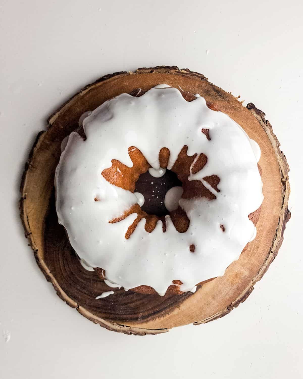 A glazed lemon bundt cake on a wooden platter.