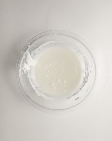A lemon glaze in a glass bowl to cover a lemon bundt cake.