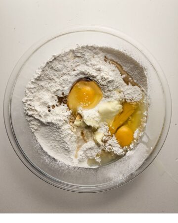 A glass bowl with flour and eggs to make a glazed lemon bundt cake.