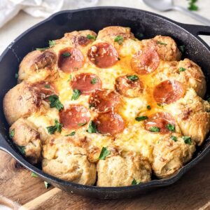 A large skillet pizza dip with round pizza balls and a center filled with cheese and pepperoni