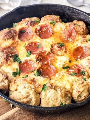 A large skillet pizza dip with round pizza balls and a center filled with cheese and pepperoni