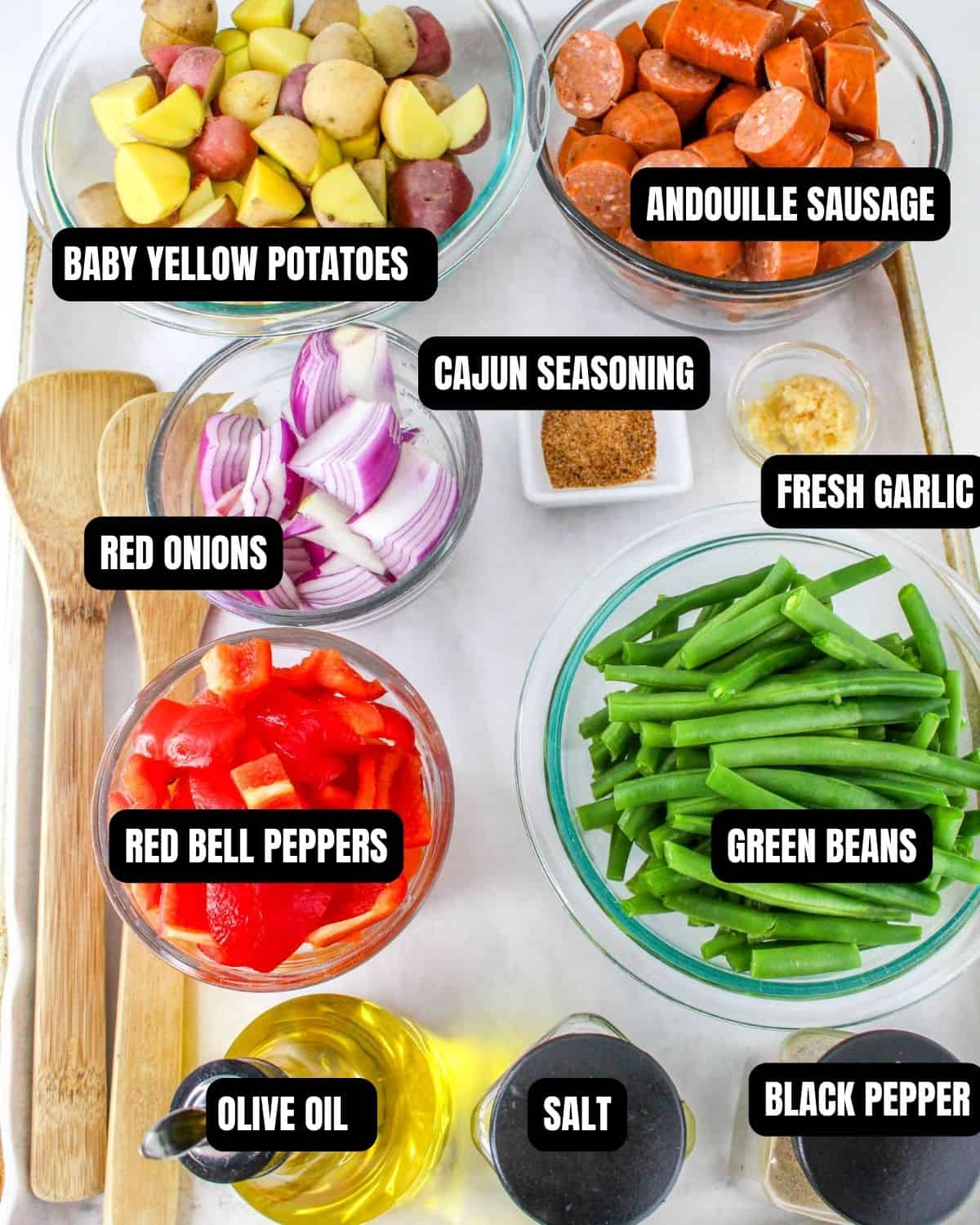 Ingredients to make a sheet pan cajun sausage dinner with text overlay.