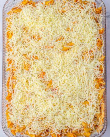 A large baking dish with chicken parm pasta casserole topped with cheese.