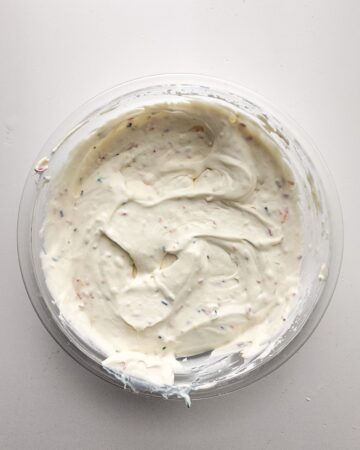 A glas bowl with a combination of heavy cream and a cak mix mixture to make a no churn birthday cake ice cream.