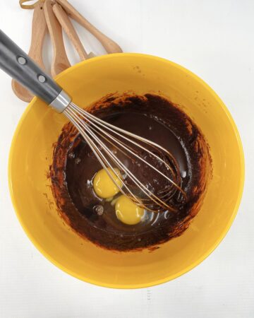A bowl of brownie batter with eggs.