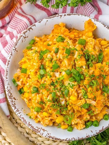 Chicken rice enchilada casserole in a bowl topped with chopped green onions and chopped cilantro.