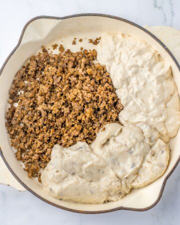 A saute pan with ground beef, cream of mushroom soup and french onion dip to make a french onion beef casserole.