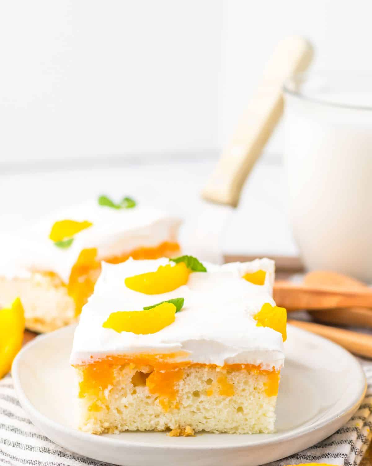 A slice of poke cake with orange gelatin filing and a whipped cream topoing.