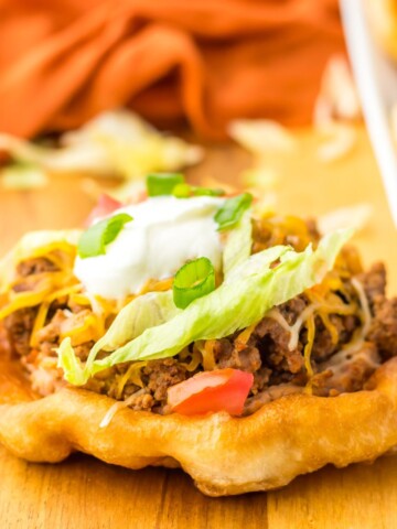 Indian fry bread taco topped with lettuce and sour cream.