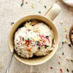 Birthday Cake Ice Cream topped with rainbow sprinkles in a mug.