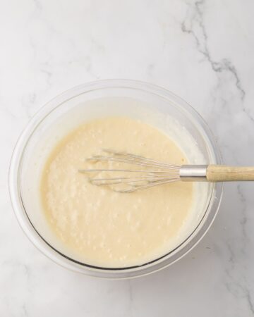 A clear bowl with cake batter to make an orange poke cake.