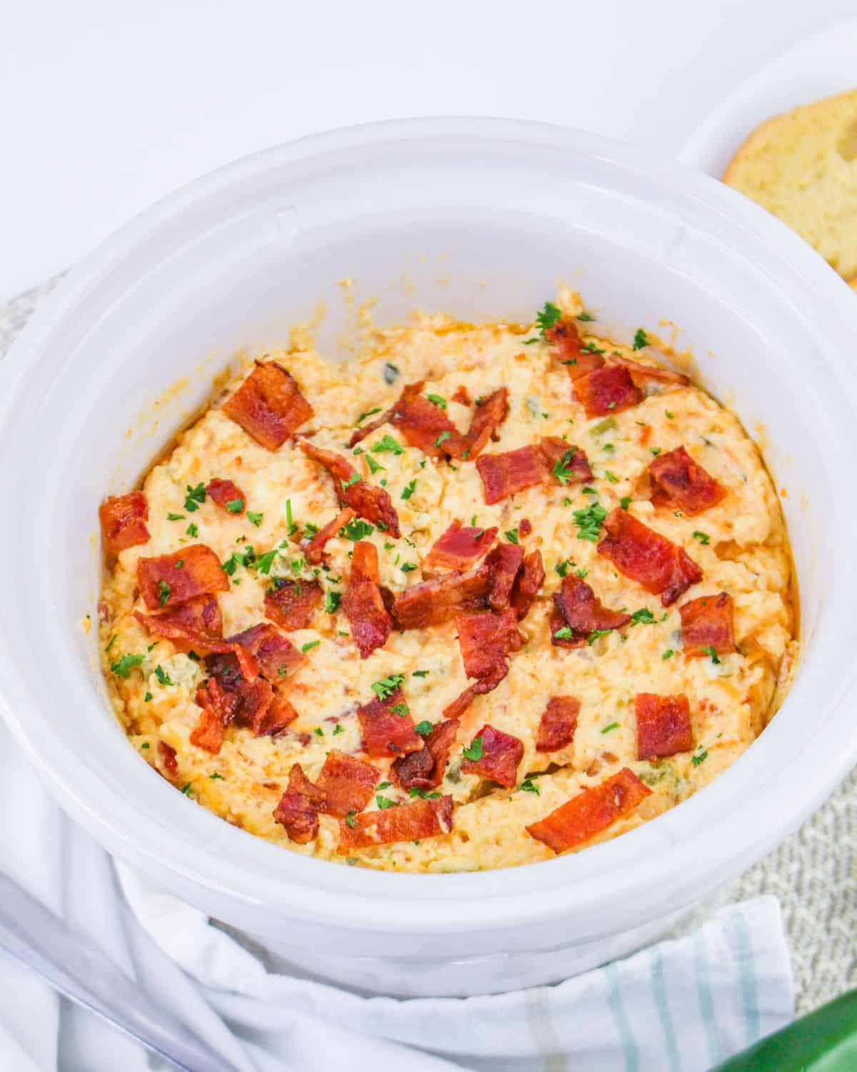 Crockpot jalapeno popper dip in a white slow cooker.