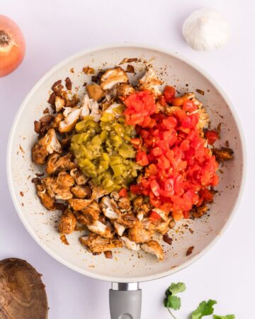 Seasoned cooked chicken with spices, green chiles, and tomatoes to make sour cream chicken enchiladas. 