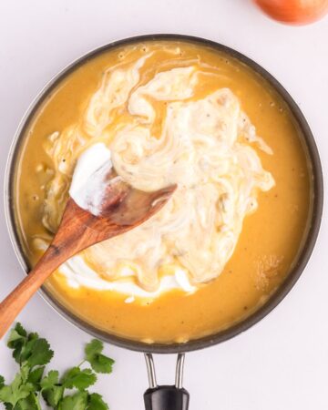 The sauce for sour cream enchilada chicken casserole in a large saute pan. 