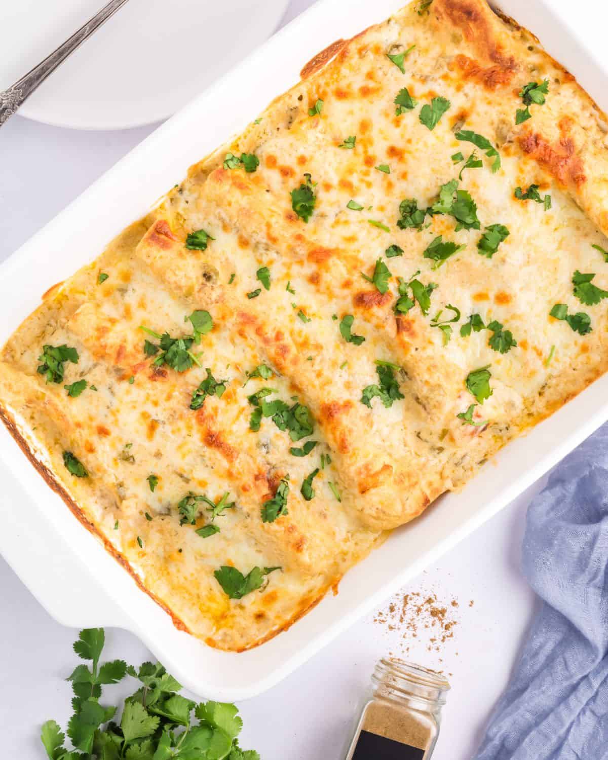 Sour cream chicken enchiladas in a large white casserole dish.