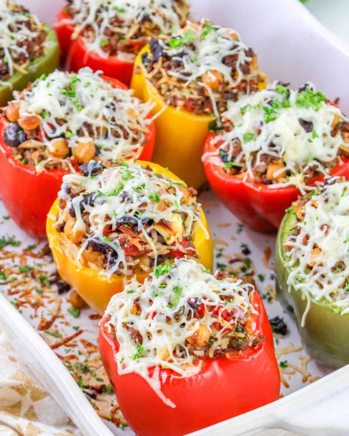 Stuffed peppers with greek flavors in a baking tray.