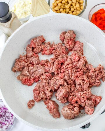 A saute pan with ground beef being browned.
