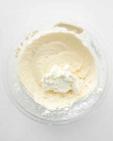 Cheesecake filling with whipped cream being added to it to make cheesecake stuffed waffle cones.